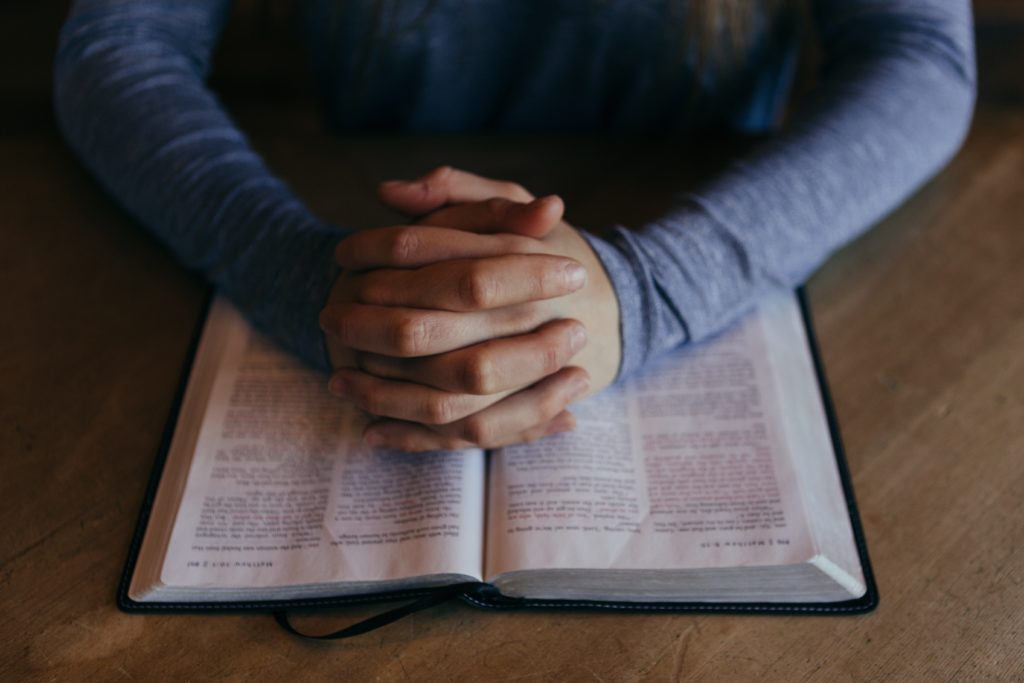 folded hands over Bible